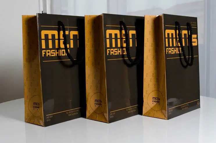 Drei schwarze orange Papiertragetaschen auf weißen Tisch